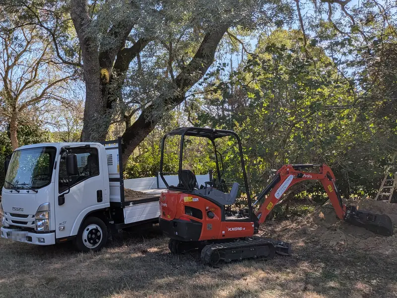 Minipelle et camion benne Assainissement Julien garés sur un terrain avant le début du chantier