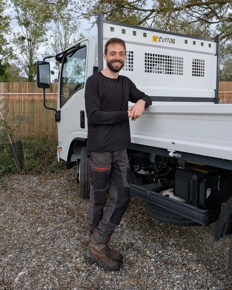 Julien, gérant d'Assainissement Julien, appuyé contre son camion benne